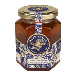 Dutch flower honey in a glass jar with a blue and white floral label.
