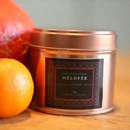 Small candle with cinnamon, mandarin, and apricot blossom scents in a copper-colored tin.