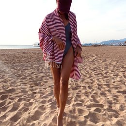 Striped red and white hammam towel with fringed edges.