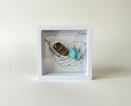 Colorful chakra stones in a wooden box, including red, blue, purple, and green stones. The stones appear to be polished and natural in shape.