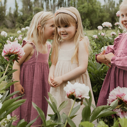 Organic cotton summer dress for girls in beige, violet, and pink colors, available in sizes 18-24 months to 7-8 years. Features a flowy, A-line silhouette with adjustable straps.