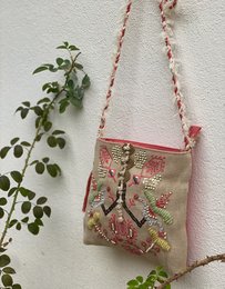  Coral embroidered canvas shoulder bag with colorful floral and butterfly patterns, featuring a braided strap and a zippered closure.