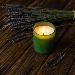 Organic scented candle with lavender fragrance in a green glass container.