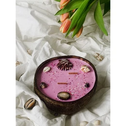 A round, tall, pink candle with floral and shell decorations, evoking a tropical, beachy vibe.