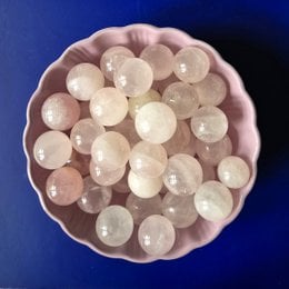 Small, round, pale pink rose quartz spheres in a pink bowl.