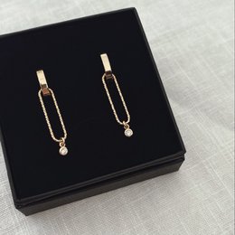 Gold-tone statement earrings with elongated links and a small pearl accent.