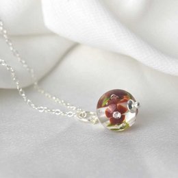 Elegant burgundy glass flower necklace charm with a delicate silver chain.