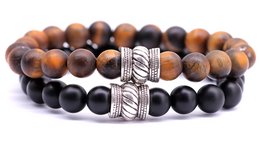 A set of beaded bracelets featuring brown tiger eye and black onyx stones, with a decorative metal accent piece.