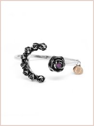  Burnished silver-tone cuff bracelet with black rose and charm details.