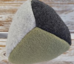 Sustainable dog toy ball made of natural materials in various color combinations including copper/light gray/black, sage/light gray/black, black, and copper brown.