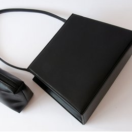 Black handbag with a simple, minimalist design. Made of durable material with a single strap for carrying.