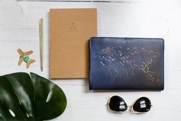 Navy blue travel notebook with embroidered world map design, perfect for journaling and note-taking on the go.