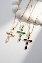  Elegant gold-toned stainless steel cross pendant with colorful gemstones. Available in white, green, and black color variants.