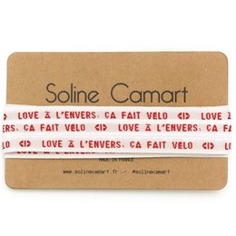 A pair of black high-top sneakers with pink laces that have the text "Love à l'envers, ça fait velo" printed on them.