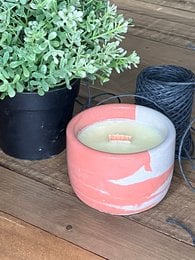 Round, concrete candle in a pink and white color with a floral design. Made of concrete material.