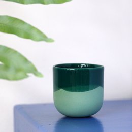 A porcelain cup in a deep forest green color, featuring a simple, minimalist design.