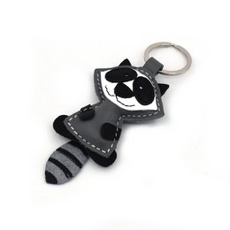 Handmade leather keychain in the shape of a raccoon with black and white details.