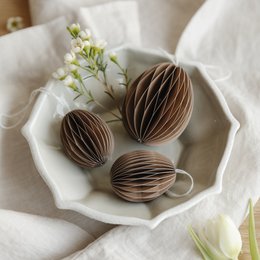 White paper Easter eggs in a decorative bowl with spring flowers.