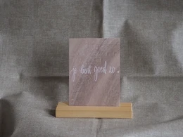 A greeting card with the text "You're good to" written in cursive handwriting on a brown background.