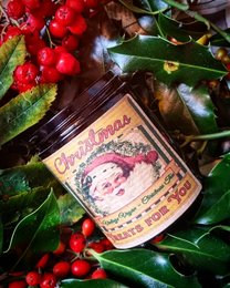 Vintage vegan Christmas tree candle with a festive scent, surrounded by holly and berries.