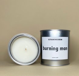 Tall, round, white scented candle with a Burning Man theme, featuring a minimalist black and white label.