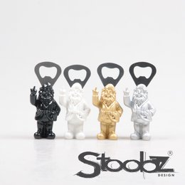  Bottle opener in the shape of a stylized character, available in black, white, gold, and silver colors. The product is designed by Stoobz.