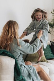 A soft, plush sea green children's bathrobe with a hood and a tie waist. Made of comfortable, absorbent material suitable for after bath or shower use.