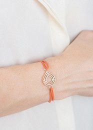Elegant bracelet with a teardrop-shaped pendant in a gold tone, featuring an adjustable orange cord for a comfortable fit.