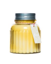 A tall, round glass candle jar with a yellow wax candle inside. The jar has a silver metal lid and a label with the brand name "Barr-Co Soap Shop" and the scent "Lemon Verbena".