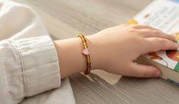 Children's bracelet made of 6 mm beads in various colors including green, purple, and pink, with a heart-shaped charm.