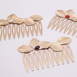 Wooden comb with leaf-shaped teeth in various colors including brique, midnight blue, noir, aniline, prusse, nude, ambre, blanc, mousse, corail, sable, and massaï.