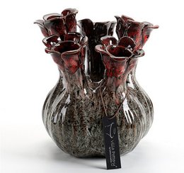 A decorative glass vase with a dark, textured surface and deep red, fluted glass elements. The vase has an organic, sculptural shape and appears to be made of a combination of glass and other materials.