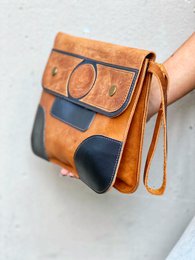  Handmade cowhide leather clutch bag in a stylish patchwork design with contrasting colors and textures.