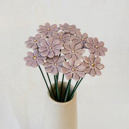 A bouquet of small, delicate dried flowers in various shades of pink, including dark blue, light blue, purple, pink, white, yellow, and red. The flowers have a simple, minimalist style and are arranged in a vase.