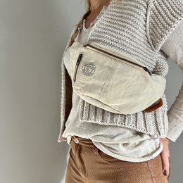  A light canvas cross-body bag with a textured, knitted pattern and a zipper closure.