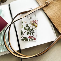 Floral luggage tag with honeysuckle design, featuring a leather strap and a white tag with space for writing personal details.