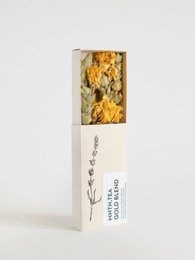 A small box containing a blend of golden tea leaves, with a simple and elegant design.