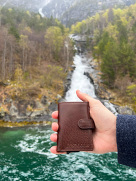 Leather card holder in cognac, brown, and black colors. Extendable design with coin and bill compartments. Suitable as a men's wallet or father's day gift.