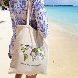 Beige tote bag with a world map graphic and the text "Travel the world change the world" printed on it. Made of durable canvas material with sturdy handles for comfortable carrying.