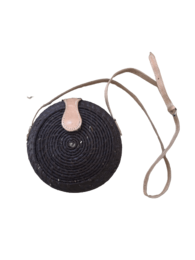 Black round crossbody bag with beige leather strap and accent.