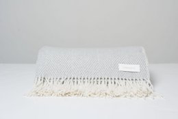 Soft, cozy herringbone-patterned throw blanket in a neutral color with fringe detailing.