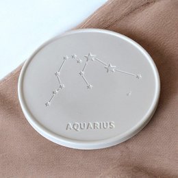  Coasters featuring the Aquarius zodiac sign constellation design. Made of ceramic material, available as a single piece or a set of 6. The coasters have a minimalist, modern style with the constellation pattern embossed on the surface.