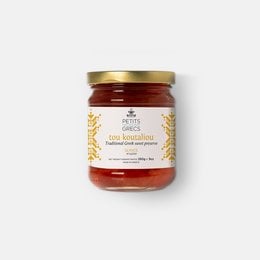 Traditional Greek quince fruit preserve in a glass jar with a gold lid. The preserve is a deep red color and appears to have a thick, spreadable consistency. The jar is surrounded by fresh quinces and cinnamon sticks, suggesting the preserve is made from natural ingredients.