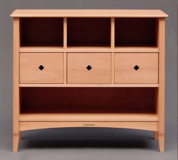 A wooden chest of drawers with three drawers and open shelving, suitable for a child's wardrobe. The design features a natural wood finish and simple, clean lines.