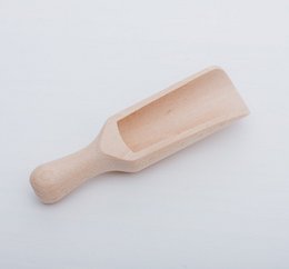 Large scoop sensory toy made of natural materials. Wooden scoop with textured, beige-colored peanuts or similar legumes.