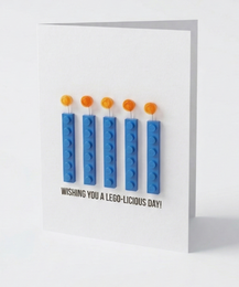  "Birthday greeting card with blue Lego bricks, orange studs, white background, playful design, multilingual text"