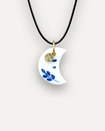 Porcelain pendant charm in a crescent moon shape with blue dot accents, available in gold or silver tone metal.