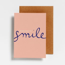 A pink postcard with the word "Smile" written in cursive text. The postcard is accompanied by a brown envelope.