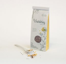 Herbal tea with floral design, featuring a round tea pot and tea cups on a rustic wooden surface.