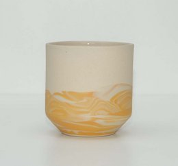 Ochre-colored ceramic mug with abstract wave pattern.